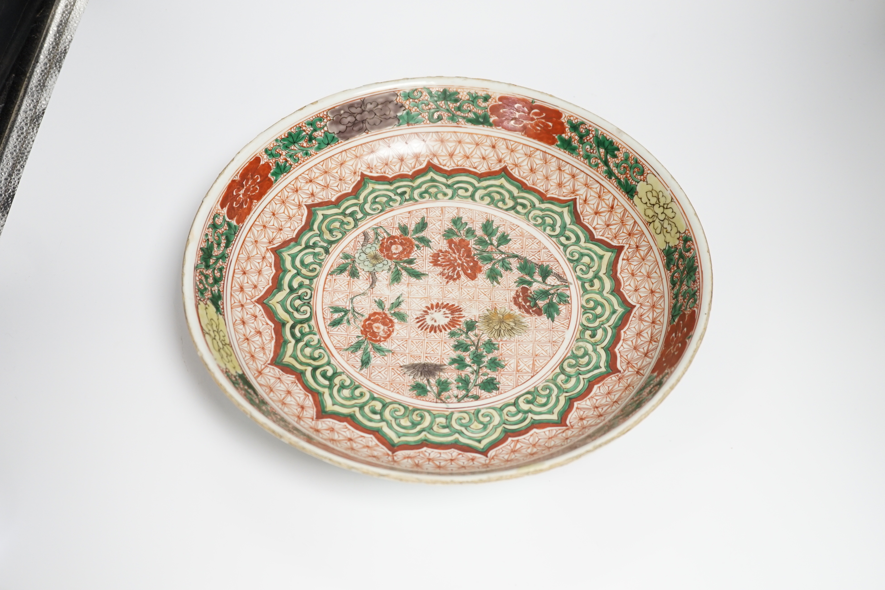 A Chinese famille verte dish, Kangxi period, decorated with flowers bands of brocade patterns, channel moulded foot, 33cm diameter